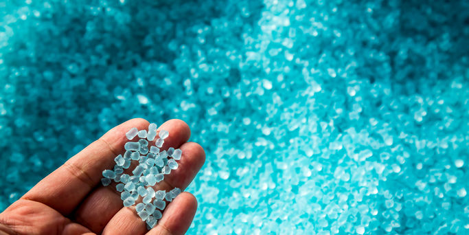 A hand hold or touching plastic pellets , plastic polymer dye granules color clear blue A hand hold or touching plastic pellets , plastic polymer dye granules color clear blue