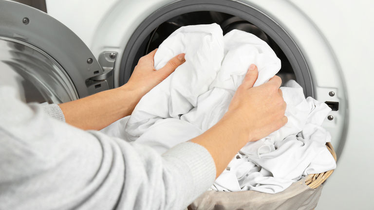 Hands getting out clean clothes from washing machine
